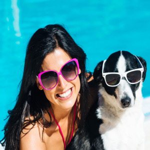 Woman and her dog by the pool wearing sunglasses
