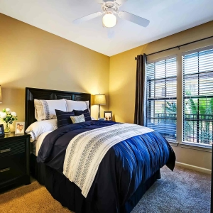 Bedroom in model home with modern furniture and large windows with lush greenery outside