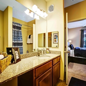 Large bathroom of model home with single sink granite vanity with door open to bedroom